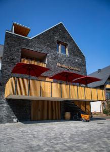 ein Gebäude mit roten Sonnenschirmen davor in der Unterkunft Rieslingquartier - Mosel Wein Hotel in Kröv