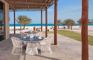 un patio con mesa y sillas y la playa en Anantara Sir Bani Yas Island Al Yamm Villa Resort, en Da‘sah