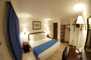 Habitación de hotel con cama y cortina azul en Hotel Del Portal, Puebla, en Puebla