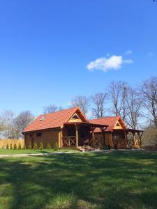 a log home with a red roof on a green field at Domki w sadzie in Wydminy