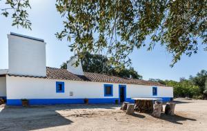 a white building with blue windows and a tree at Monte do Serrado de Baixo - T4 in Évora