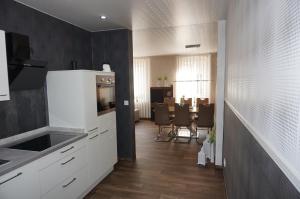 cocina con armarios blancos y comedor en Super Erdgeschosswohnung, en Königslutter am Elm