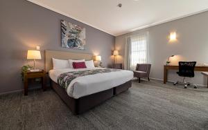 een hotelkamer met een groot bed en een bureau bij Coachmans Inn Warwick in Warwick