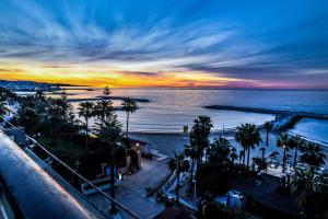 a sunset over the ocean and a beach with palm trees at Gran Hotel Guadalpín Banus in Marbella