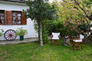 2 Stühle und ein Tisch im Garten mit einem Baum in der Unterkunft Marelmy in Mouresi