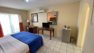 a bedroom with a bed and a desk with a television at Bay Gardens Inn in Gros Islet