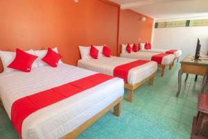 um quarto com três camas com lençóis vermelhos e brancos em OYO Hotel Meson de la Concepcion em Zacatecas