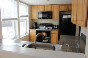 a kitchen with a sink and a black refrigerator at Town Square Condominiums in Waterville Valley