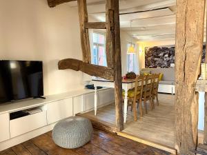 ein Wohnzimmer mit einem TV und einem Tisch mit Stühlen in der Unterkunft Monschau-Auszeit: Historisch wohnen direkt am Bach in Monschau