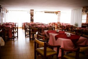 a restaurant with tables and chairs with red table cloth at Hotel Menossi in Río Cuarto