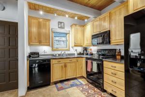 a kitchen with wooden cabinets and black appliances at Peaceful creek view from the deck! Walk to Shuttle in Vail