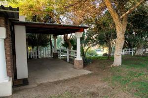 a porch of a house with a fence and a tree at Ikaia River Lodge in Keimoes