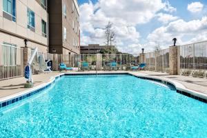 Holiday Inn Express & Suites Round Rock Austin North, an IHG Hotel في راوند روك: مسبح وكراسي زرقاء ومبنى