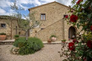 un edificio de piedra con un patio con rosas rojas en San Martino agli Ulivi, en Cortona