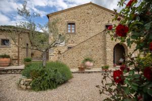 a stone building with a courtyard with red roses at San Martino agli Ulivi in Cortona