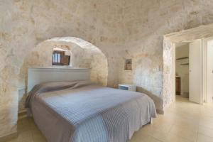 a bedroom with a bed in a stone wall at Antica Tenuta dei Trulli in Alberobello +61 photos