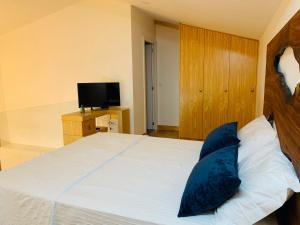 a bedroom with a large white bed with blue pillows at L'atelier Apartments (Pintura) in Guimarães