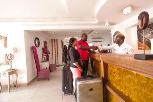 un grupo de personas de pie en un bar con equipaje en The Swiss Hotel Freetown en Freetown