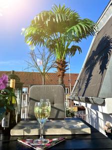 a glass of wine sitting on a table with a palm tree at Four Individual Beautiful Spacious Rooms In Stylish Apartment in Copenhagen