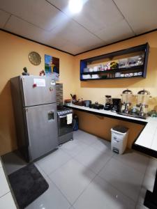 a kitchen with a refrigerator and a counter with pots and pans at Toucan Hostel in Alajuela City