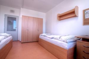 1 dormitorio con 2 camas y armario de madera en Domov mládeže - Ubytování Sokolov en Sokolov