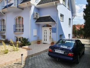 un coche aparcado frente a una casa azul y blanca en Laguna Apartmanház, en Hévíz