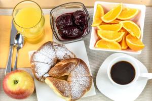 a table with a breakfast of bread and oranges and a cup of coffee at Hotel Club Maria Sidari in Sidari
