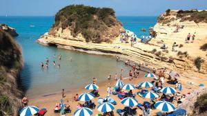 a group of people on a beach with umbrellas at Hotel Club Maria Sidari in Sidari