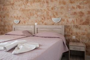 a bedroom with two beds with pink sheets and a brick wall at Hotel Club Maria Sidari in Sidari