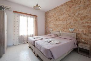 a bedroom with two beds and a brick wall at Hotel Club Maria Sidari in Sidari