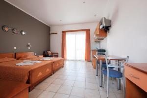 a bedroom with two beds and a table and a kitchen at Hotel Club Maria Sidari in Sidari