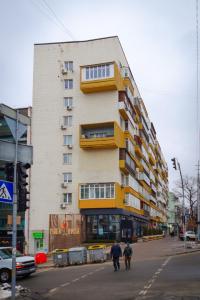 two people walking down a street in front of a building at 112 вулиця Велика Васильківська in Kyiv