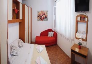 una camera con un letto e una sedia rossa di Apartments Liza - 80 M from the sea a Korčula