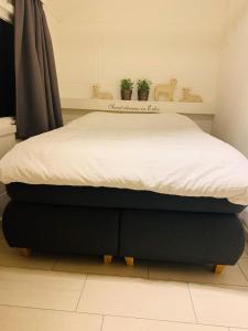 um quarto com uma cama com um lençol branco em Bungalow 72 em Exloo