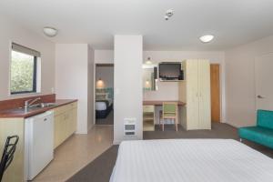 ein Schlafzimmer mit einem Bett und eine Küche mit einem Waschbecken in der Unterkunft Bella Vista Motel New Plymouth in New Plymouth