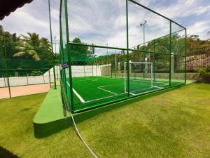 a tennis court with a net on a grass field at Flat Praia dos Carneiros in Tamandaré