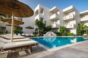 een zwembad in een hotel met ligstoelen en parasols bij Parasol Luxury Hotel & Suites Adults Only in Karpathos
