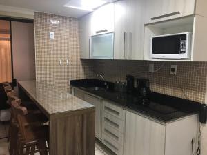 a kitchen with a sink and a microwave at Atlântico Flat 110 in Natal