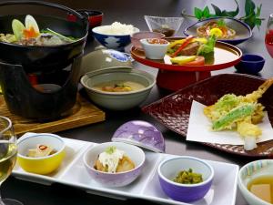 une table avec des assiettes et des bols de nourriture dans l'établissement Nomoto Ryokan Matsunoyama Onsen, à Tōkamachi