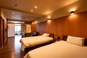 a hotel room with two beds and a chair at Kannawaen in Beppu