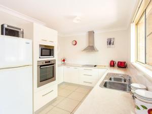 a white kitchen with a sink and a refrigerator at 1/4 Huntly Close in Tuncurry