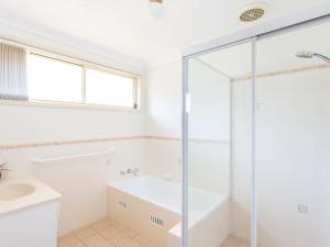 a bathroom with a shower and a tub and a sink at 1/4 Huntly Close in Tuncurry