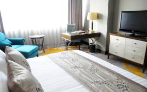 um quarto de hotel com uma cama, uma secretária e uma televisão em Gubei Garden Hotel Shanghai Hongqiao em Xangai
