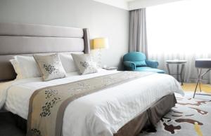 um quarto com uma cama grande e uma cadeira azul em Gubei Garden Hotel Shanghai Hongqiao em Xangai