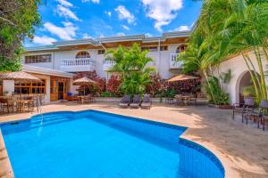 a pool in front of a house with palm trees at Buena Vista Chic Hotel in Alajuela City