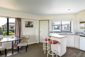 
a kitchen with a table, chairs and a sink at The Beachcomber Hotel in Nelson
