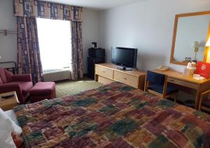 a hotel room with a bed and a television at Norwood Inn and Suites - Roseville in Roseville