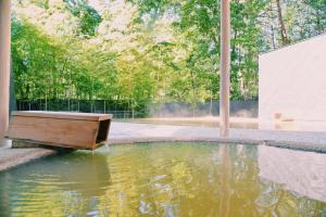 a pool of water with a wooden bathtub in a yard at HOTEL KEYFOREST HOKUTO in Hokuto