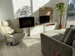 een woonkamer met een tv en een bank en een stoel bij La Cooconing in Fresnicourt-le-Dolmen