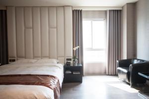 Un dormitorio con una cama y una silla y una ventana. en Grand Crystal Hotel, en Hsinchu City